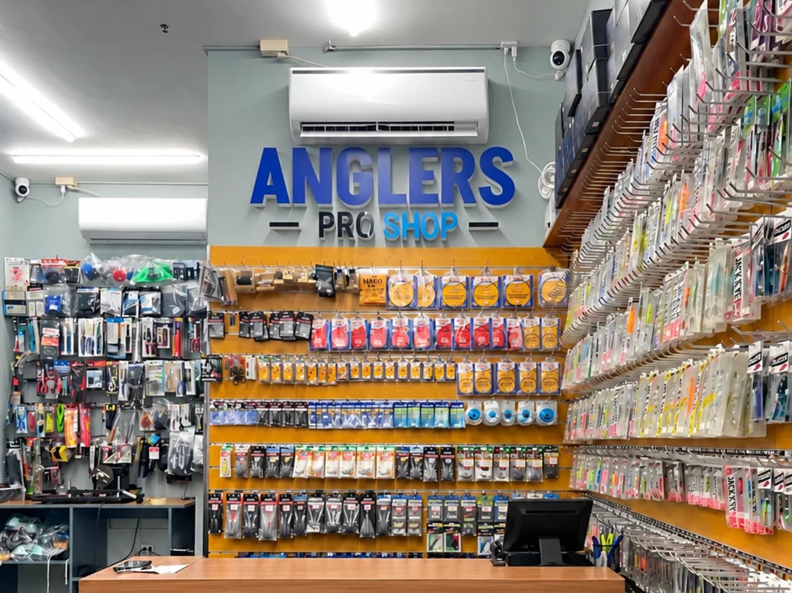 Inside Anglers Pro Shop: the counter under the sign and the wall of lures